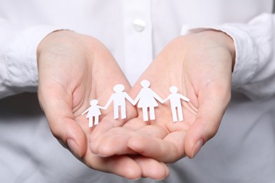 Woman holding paper family figures, closeup. Insurance concept