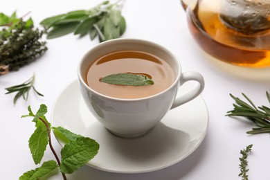 Aromatic herbal tea with thyme, rosemary, mint and sage on white table