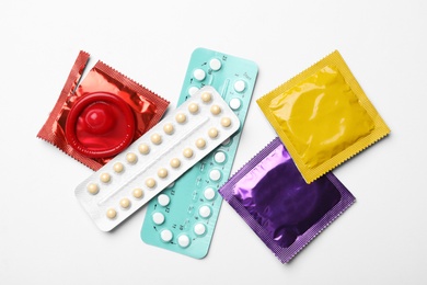 Condoms and birth control pills on white background, top view. Safe sex concept
