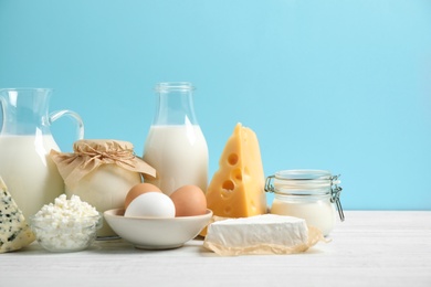 Photo of Different dairy products on white table against blue background