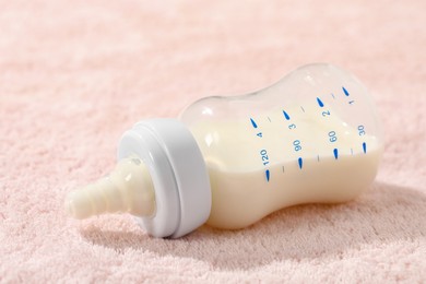 Photo of Feeding bottle with baby formula on soft towel