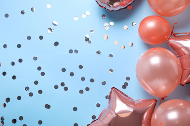 Colorful balloons and confetti on light blue background, flat lay. Space for text