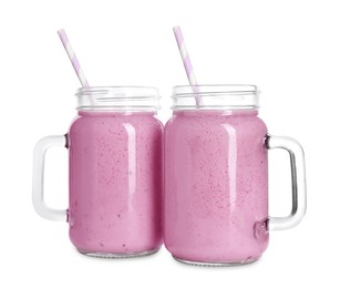Delicious blackberry smoothie with straws in mason jars on white background