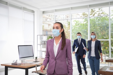 Office employees in respiratory masks at workplace