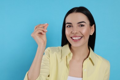 Young woman snapping fingers on light blue background