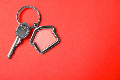 Key with trinket in shape of house on red background, top view and space for text. Real estate agent services