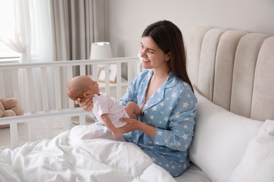 Happy young mother with her cute newborn baby in bed at home