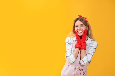 Young housewife in gloves on yellow background. Space for text