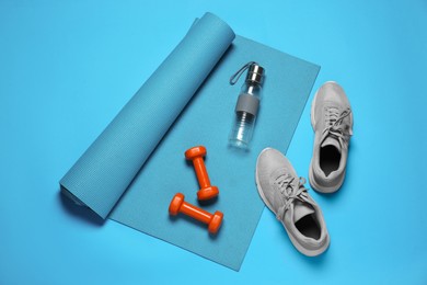 Exercise mat, dumbbells, shoes and bottle of water on turquoise background, flat lay