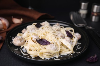 Photo of Delicious pasta with mushrooms on black table, closeup