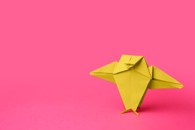 Photo of Origami art. Handmade green paper bird on pink background, space for text