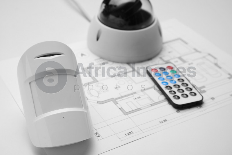 CCTV camera, remote control, movement detector and building plan on white background, closeup. Home security system