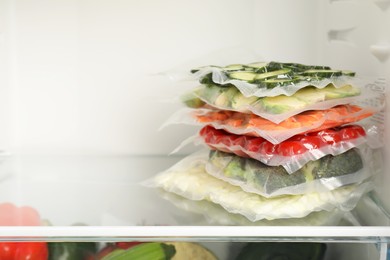 Photo of Vacuum bags with different vegetables in fridge, space for text. Food storage