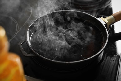 Photo of Frying pan with hot used cooking oil on stove