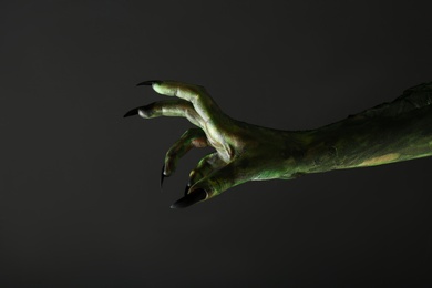 Scary monster on black background, closeup of hand. Halloween character