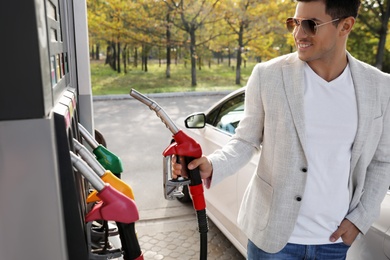 Man taking fuel pump nozzle at self service gas station