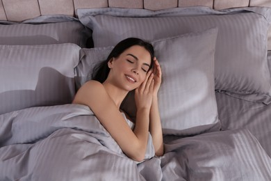 Woman sleeping in comfortable bed with light grey striped linens