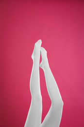 Woman wearing white tights on crimson background, closeup of legs