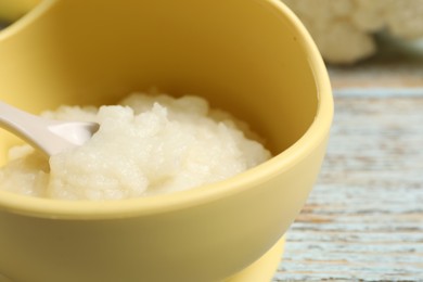 Photo of Baby food. Bowl with cauliflower puree on rustic wooden table, closeup