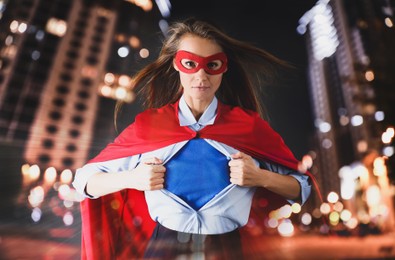 Confident businesswoman wearing superhero costume under suit and beautiful cityscape in night on background