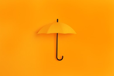 Bright toy umbrella on orange background, top view