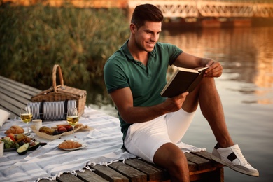 Man reading book on pier at picnic
