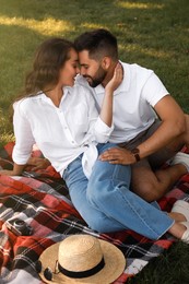 Lovely couple enjoying time together on picnic plaid in park