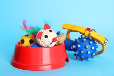 Various pet toys, collar and bowl on light blue background