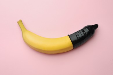 Banana with condom on pink background, top view. Safe sex concept