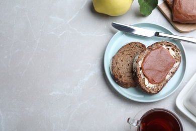 Tasty sandwich with quince paste served for breakfast on light grey marble table, flat lay. Space for text