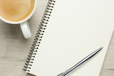 Photo of Blank notebook, cup of coffee and pen on white wooden table, flat lay