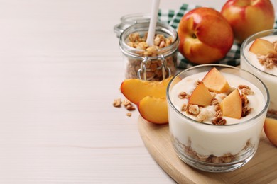Delicious yogurt with fresh peach and granola on white wooden table, space for text