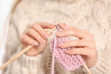 Young woman in cozy warm sweater knitting with needles, closeup