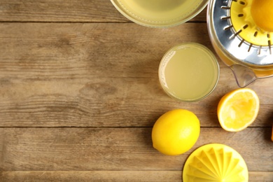 Freshly squeezed lemon juice on wooden table, flat lay. Space for text
