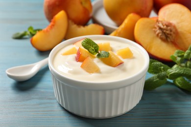 Delicious yogurt with fresh peach and mint on light blue wooden table