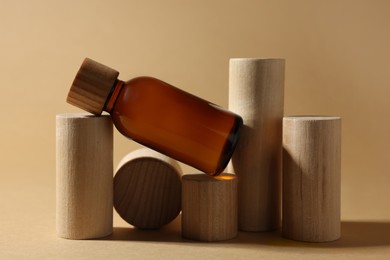 Photo of Composition with glass bottle of cosmetic product on dark beige background