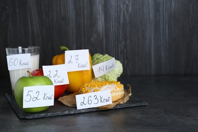Food products with calorific value tags on black table, space for text. Weight loss concept