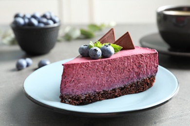 Plate with piece of tasty blueberry cake on gray table