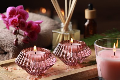 Photo of Beautiful spa composition with burning candles and different care products on wooden table, closeup