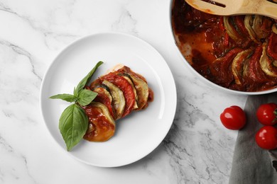 Photo of Delicious ratatouille served with basil on white marble table, flat lay
