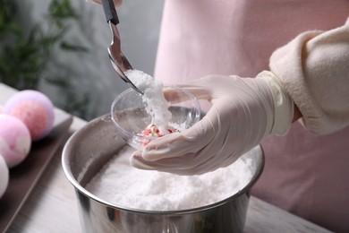 Woman in gloves making bath bomb at table indoors, closeup