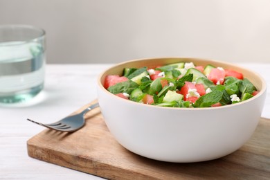 Delicious salad with watermelon, cucumber, arugula and feta cheese served on white wooden table