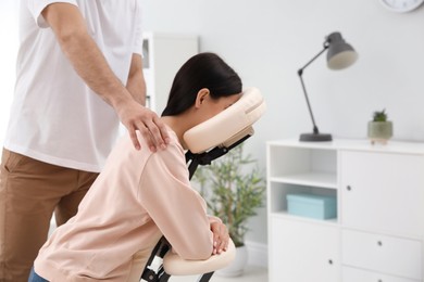 Woman receiving massage in modern chair indoors