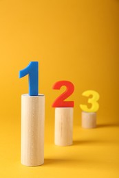 Photo of Numbers on wooden blocks against pale orange background. Competition concept