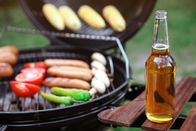 Bottle of beer on barbecue grill shelf outdoors