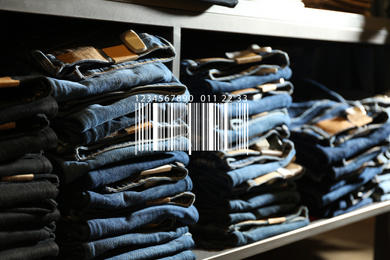 Barcode and collection of stylish jeans on shelf in wholesale shop