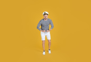 Serious sailor showing strength on yellow background