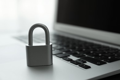 Photo of Metal lock and laptop on light background, closeup. Cyber security concept