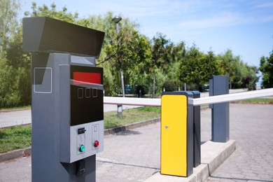Photo of Modern road barriers and parking meter outdoors on sunny day