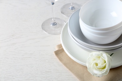 Dishware, napkin and eustoma flower on light table, closeup. Space for text